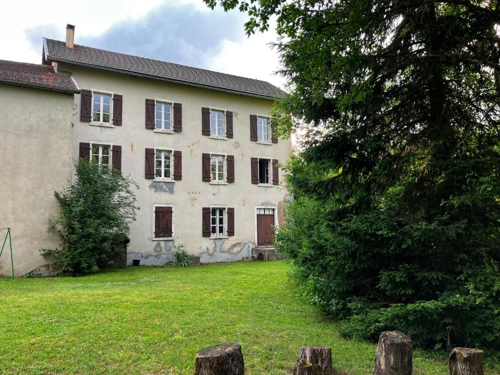 une grande maison avec une cour et un arbre dans l'établissement Gîte du Moul'Ain - Entre Terres et Sommets, à Le Poizat