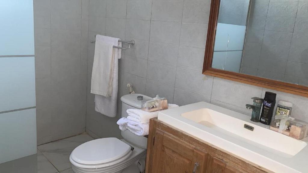 a bathroom with a toilet and a sink and a mirror at Maya, Entire Apartment, Mbour, 3 air-conditioned bedrooms in Mbour