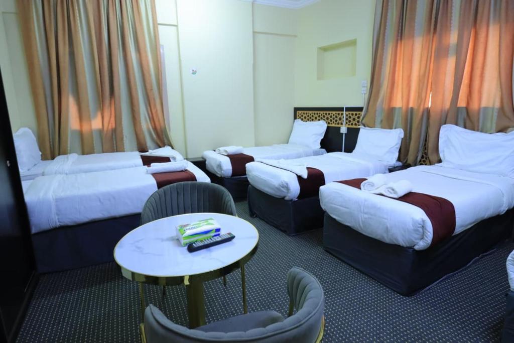 Cette chambre d'hôtel comprend 4 lits, une table et des chaises. dans l'établissement فندق جواد الحرم الفندقية, à Az Zahrāʼ