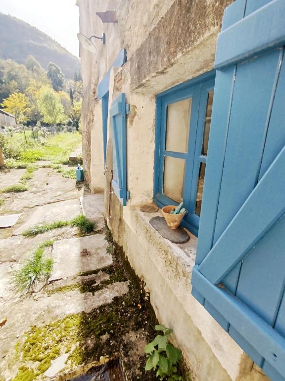 an old building with a blue window and a bowl at Maison avec jardin aux Cabannes - Ariège in Les Cabannes