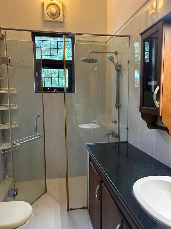 a bathroom with a glass shower and a sink at Paradise Villa in Kandana