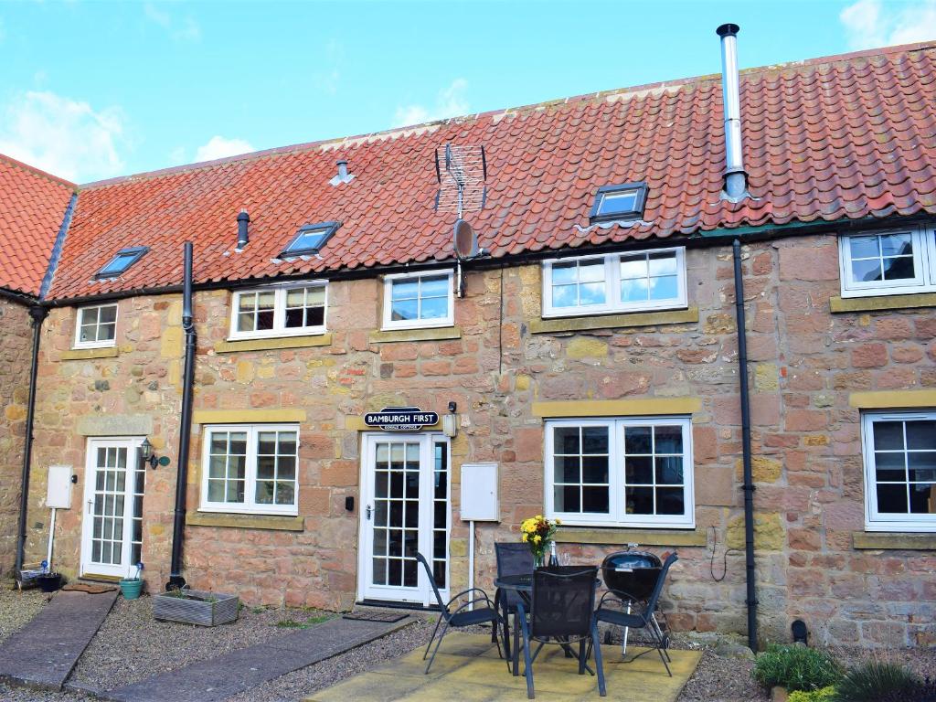 a brick building with a table and chairs in front of it at Annie Oswalds Cottage in Lucker