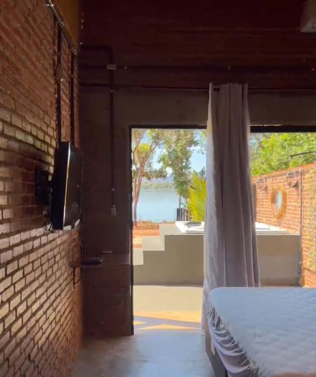 a room with a bed and a door with a window at Hotel Pousada dos Ipês in Minaçu
