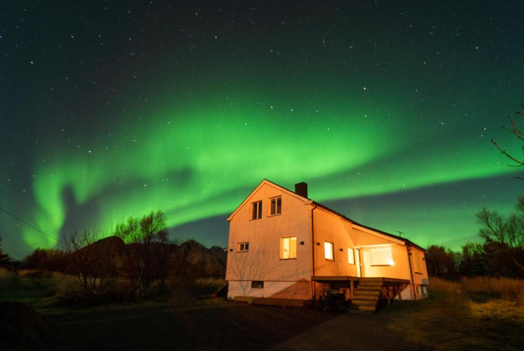 an old house with the aurora in the sky at Casa Hikari - Lofoten Retreat in Vestvågøya