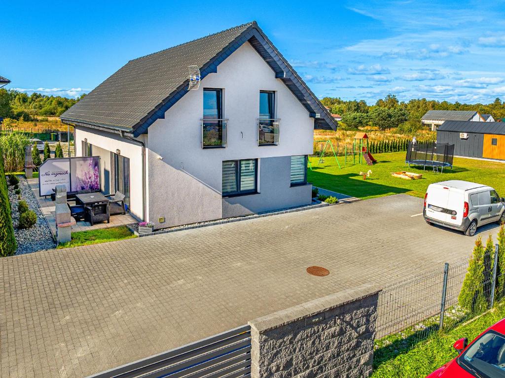 a white house with a van parked in a driveway at Domki apartamentowe Na wrzosach in Jastrzębia Góra