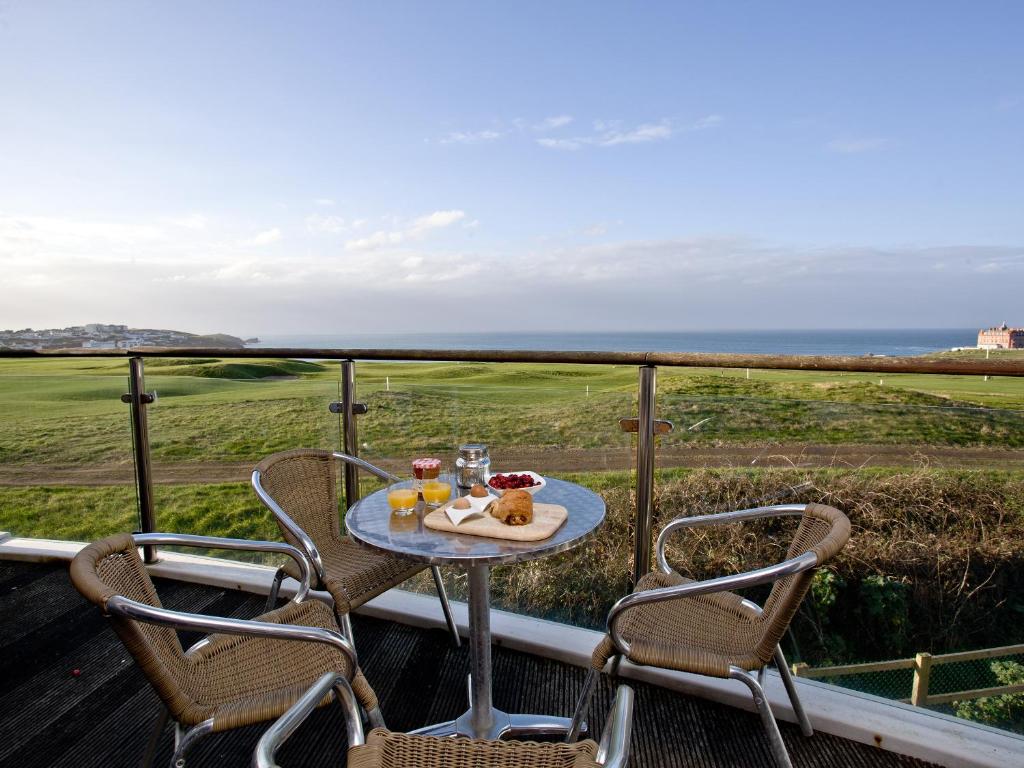 a table and chairs on a balcony with a view of the ocean at Fistral View At Bredon Court in Newquay
