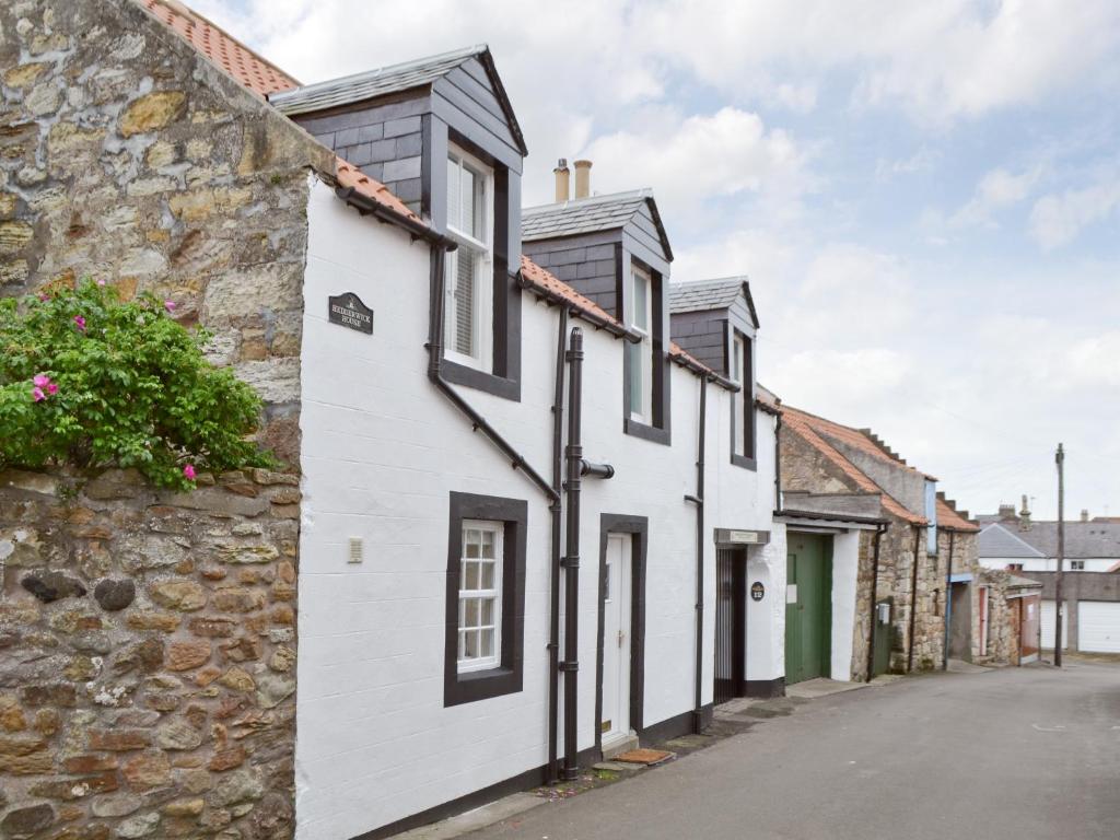 een rij witte huizen met zwarte daken bij Hedderwick House in Pittenweem