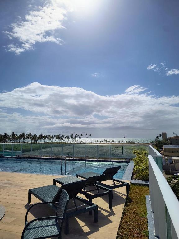 - une terrasse avec 2 tables de pique-nique et une piscine dans l'établissement Porto de Galinhas - Cupe Garden Flat, à Porto de Galinhas