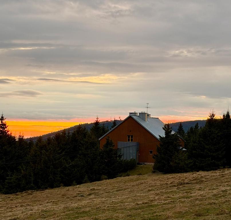 a barn on a hill with the sunset in the background at Chalet close to the Clouds in Špindlerův Mlýn