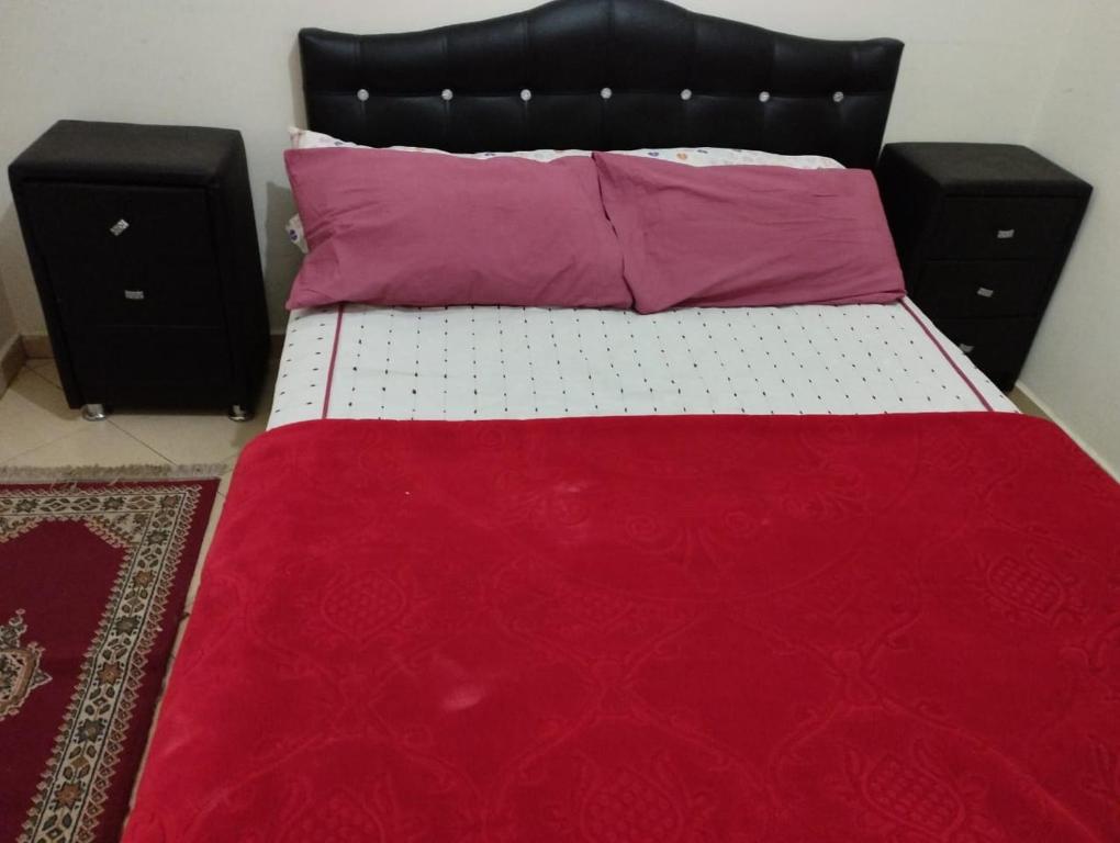 a bed with a red blanket and two pillows on it at Riyad maison in Ifrane