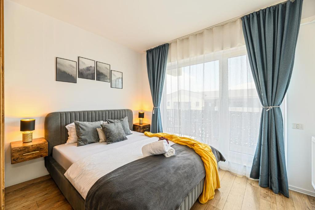 ブラショヴにあるMountain Breeze Luxury Apartment AC & Parcare Privatăのベッドと大きな窓のある寝室
