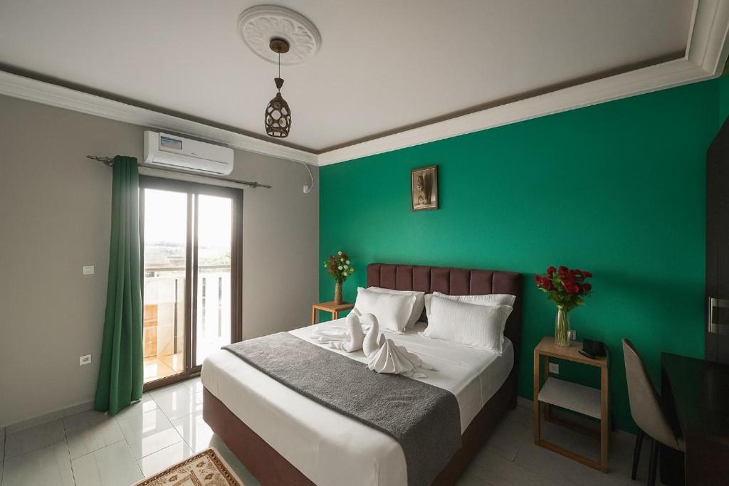a bedroom with a green wall and a bed at Résidence JTC in Douala