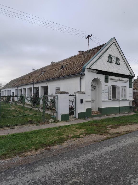 a white house with a black roof on a street at Sobe i apartman Berecz in Kopačevo