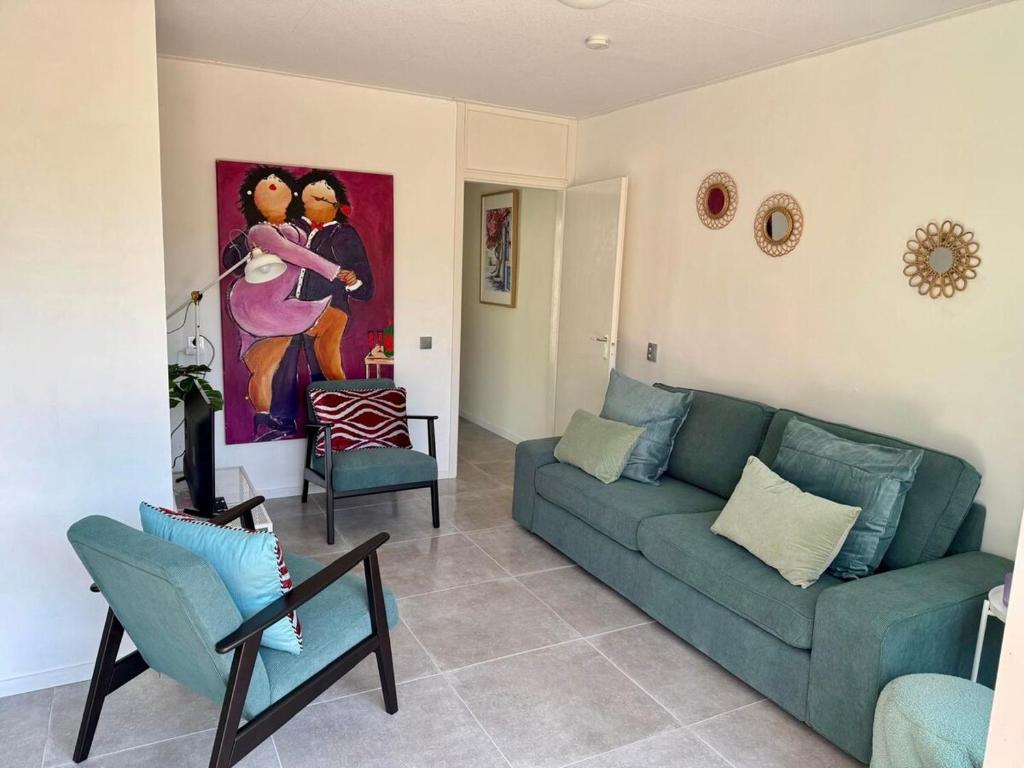a living room with a couch and chairs and a painting at Villa Dune I in Ouddorp