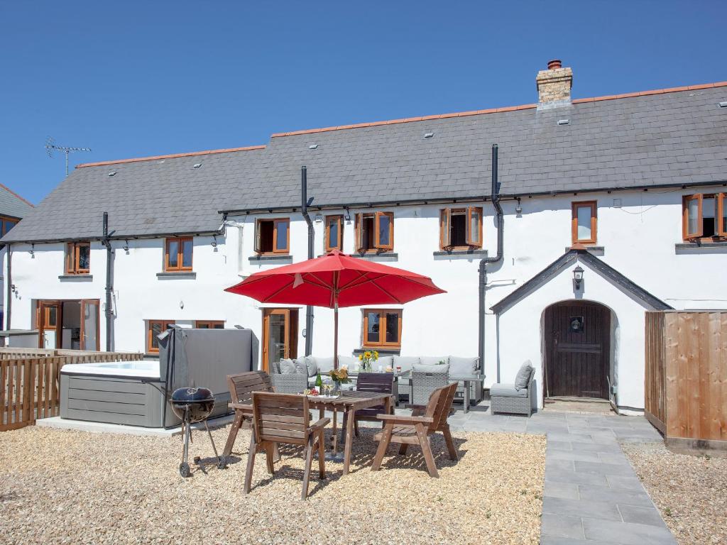 eine Terrasse mit einem Tisch und einem roten Regenschirm in der Unterkunft Four Seasons Cottage in Langtree