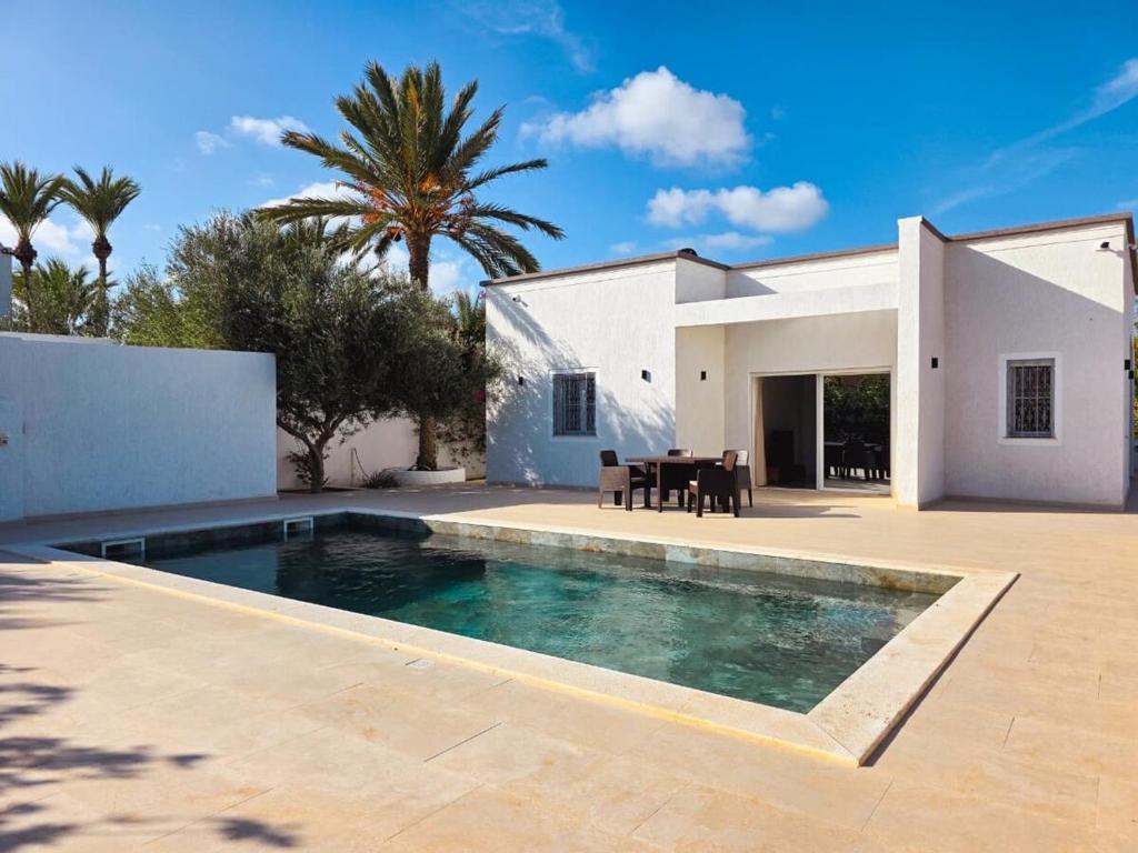 a villa with a swimming pool in front of a house at Tezdaine's garden in Bin Rhilouf