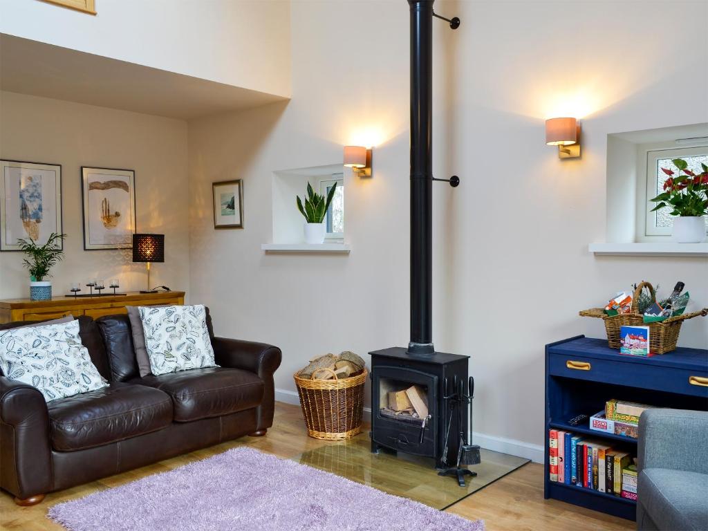 a living room with a couch and a stove at Birch Tree Cottage in Edzell