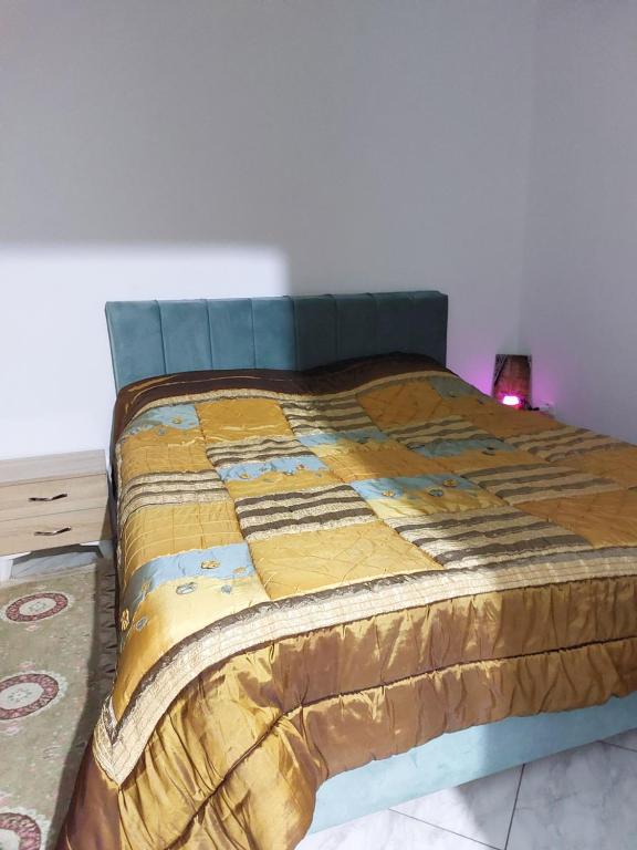 een bed in een slaapkamer met een blauwe en gele deken bij Location saisonnière entre mer, forêt et calme in Raʼs al Jabal