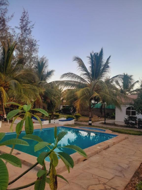a swimming pool in a yard with palm trees at Villa Paradise in Diani Beach