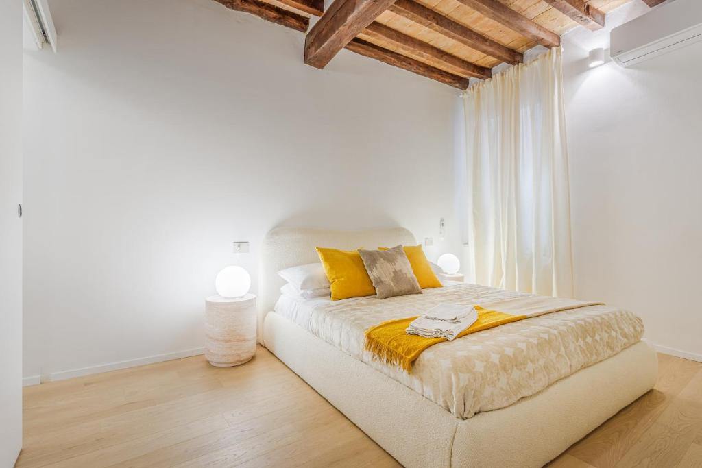 a white bedroom with a bed with yellow pillows at Nebbia sul Naviglio - Rua Frati 34 - Boutique Apartment in Modena