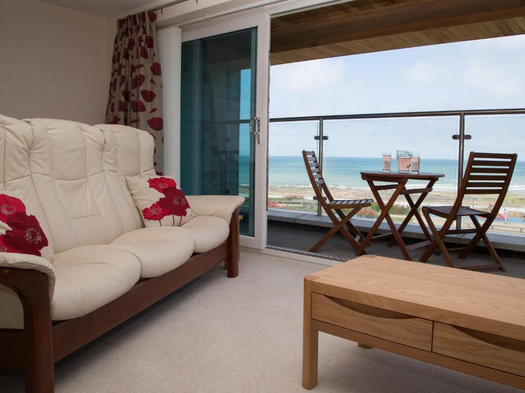 een woonkamer met een witte bank en uitzicht op de oceaan bij Apartment 5 Latitude 51 Westward Ho! in Westward Ho
