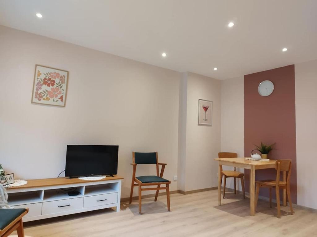 ein Wohnzimmer mit Fernseher und Tisch und Stühlen in der Unterkunft Parenthèse Vosgienne in Cornimont