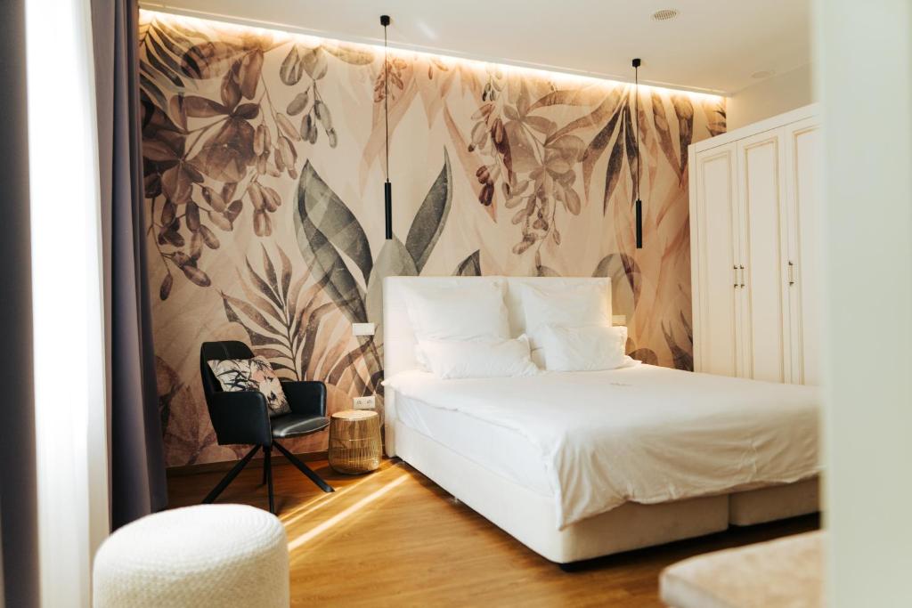 Un dormitorio con una cama blanca y una silla. en The Kepos Hotel Erlangen, en Erlangen