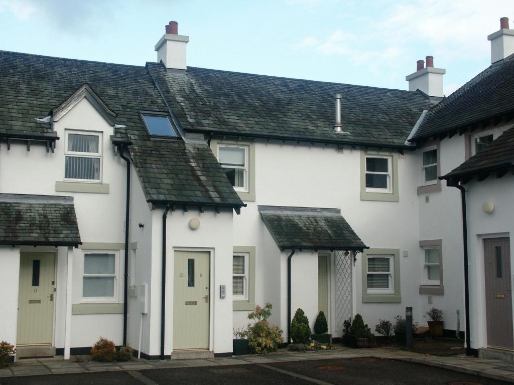 a row of white houses with green doors at 9 Howrah's Court in Keswick