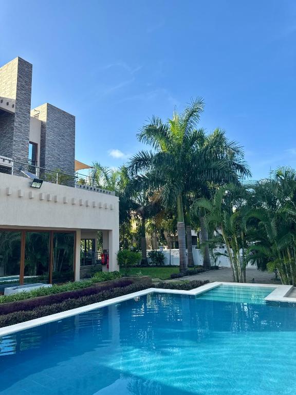 a swimming pool in front of a building with palm trees at 5-Bedroom Luxury Villa with Pool, Near Diani Beach in Diani Beach