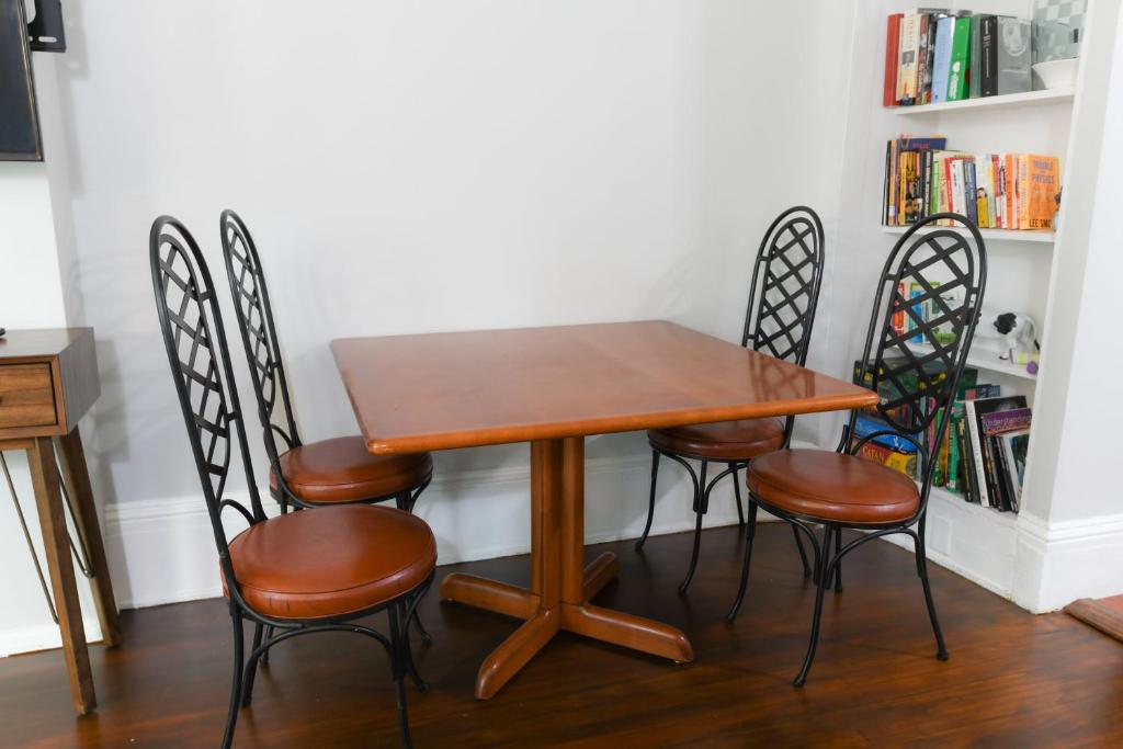 a wooden table with four chairs and a book shelf at Fully Remodeled, Charming Victorian Home in Rochester