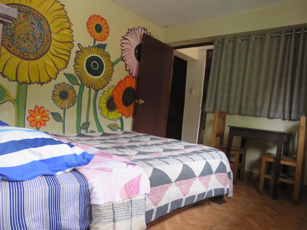 a bedroom with a bed with a flower mural on the wall at Coca Runa Wasi Hostel in Pisac