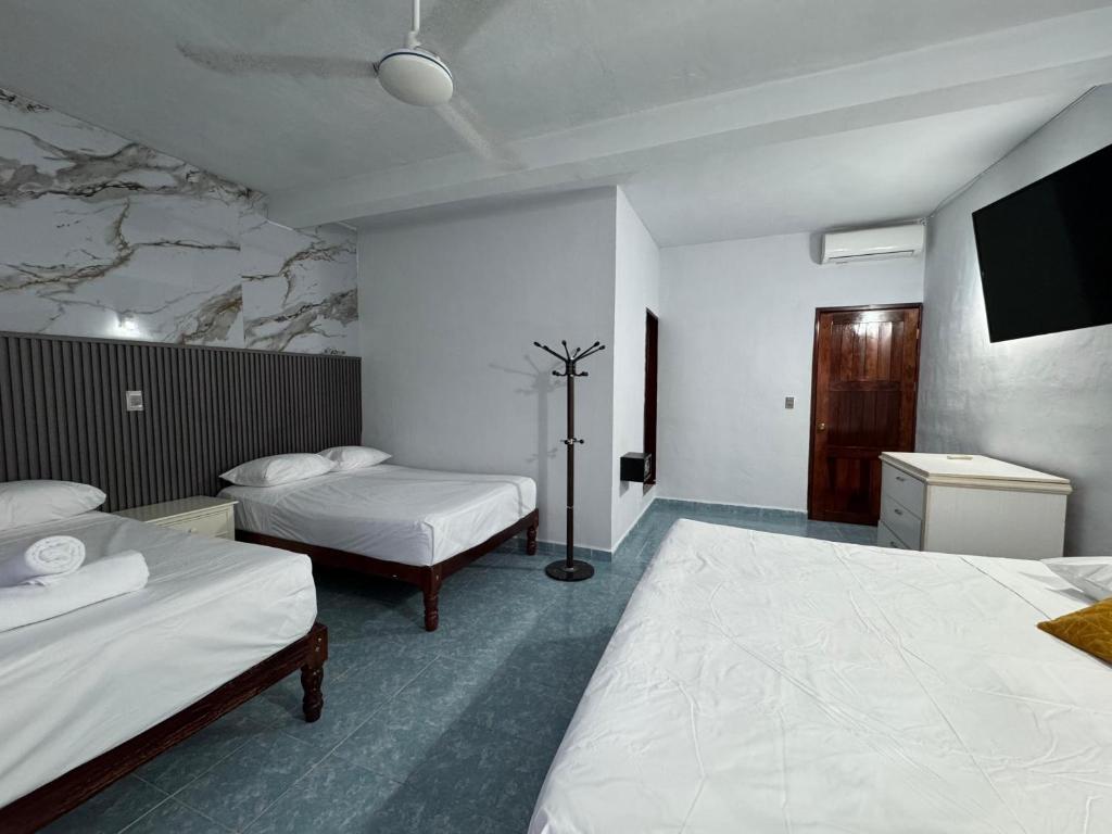 a hotel room with two beds and a flat screen tv at Hotel Mirador--gratis bicicletas in Bacalar