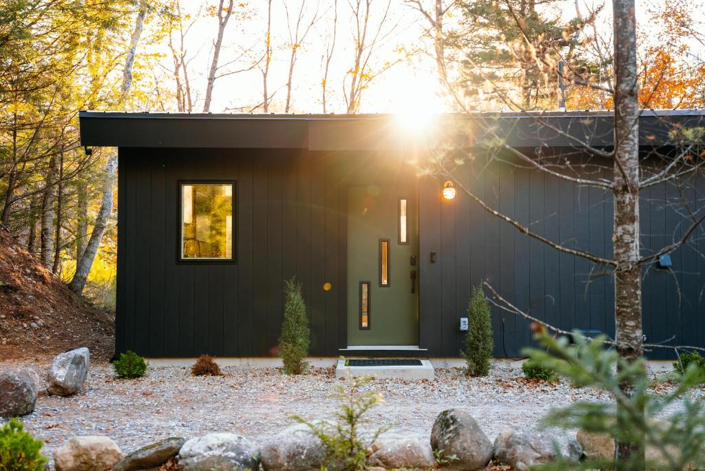 a small house with a green door in the woods at Cozy Luxury Cabin w Hot Tub, Fire Pit, King Bed in Newry