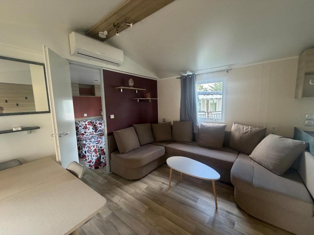 a living room with a couch and a table at Bungalow 507 3ch wifi Camping Siblu Lac de Rêves in Lattes