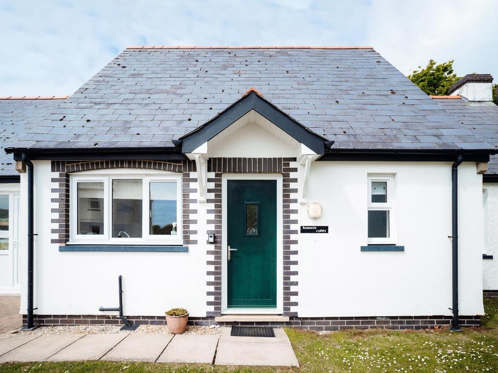 a small white house with a green door at Bosun's Cabin - Uk6719 in Lydstep