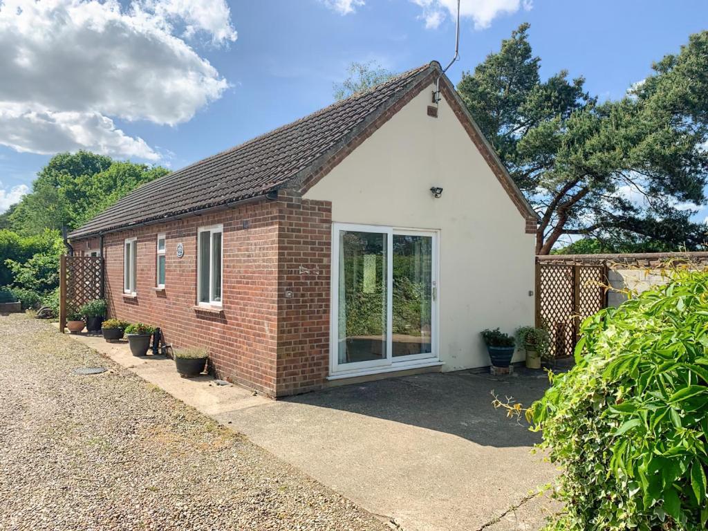 een klein bakstenen huis met een groot raam bij The Conifers in Hevingham