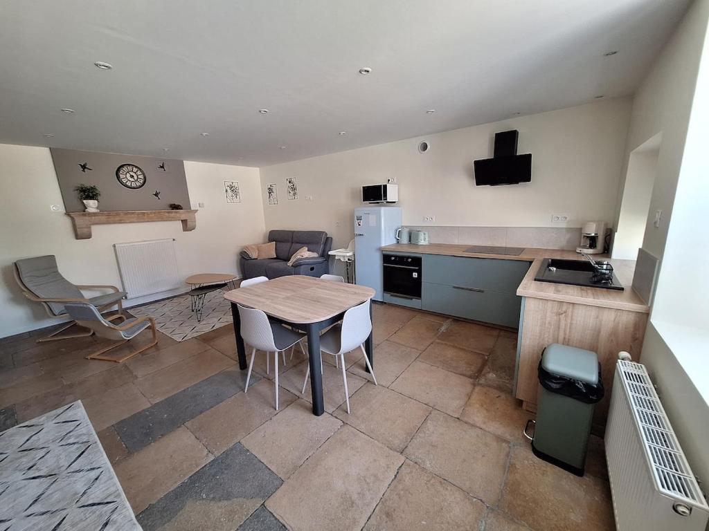 a kitchen and living room with a table and chairs at Chez Riri in Saints-Geosmes