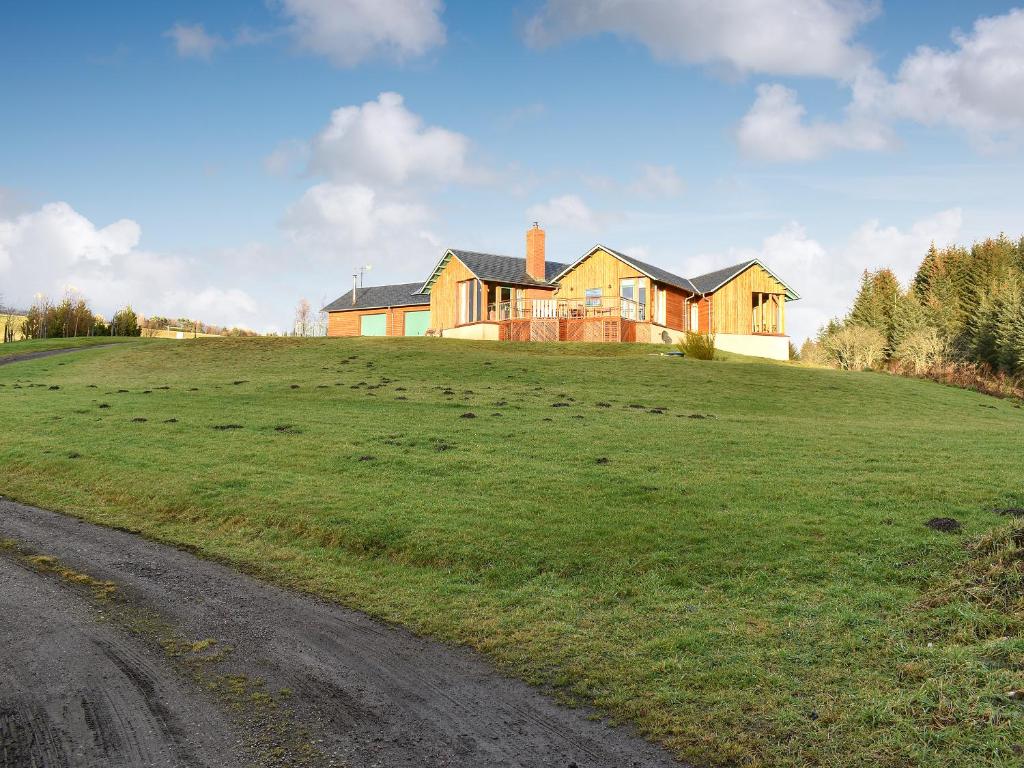 a house on top of a grassy hill with a road at Mill Of Burncrook in Glenlivet