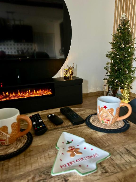 a table with two coffee cups and a christmas tree at La Ptite Maison Ardennaise in Rilly-sur-Aisne