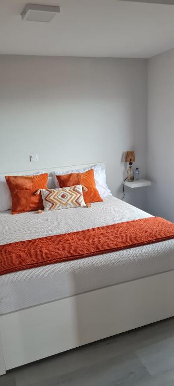 a white bed with orange and white pillows on it at Refúgio das Regadinhas in Santa Cruz