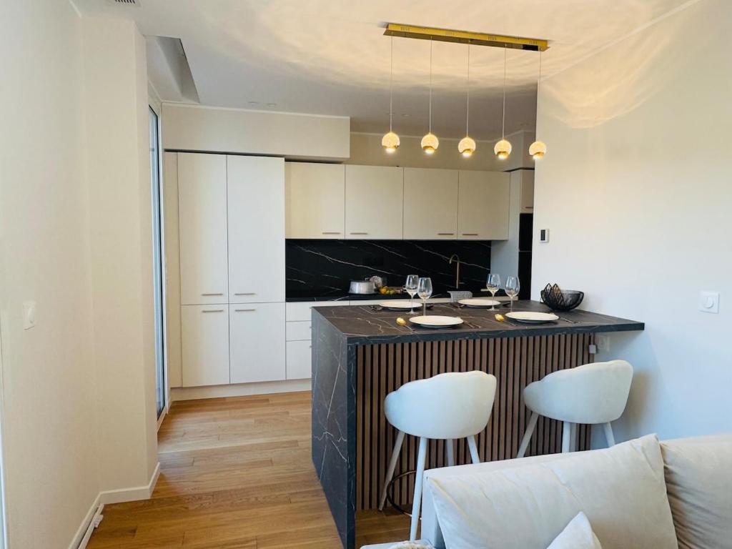 Una cocina con una barra con dos taburetes blancos. en LE PALAIS DIANE - Apt cosy, Moderne et Climatisé, en Niza