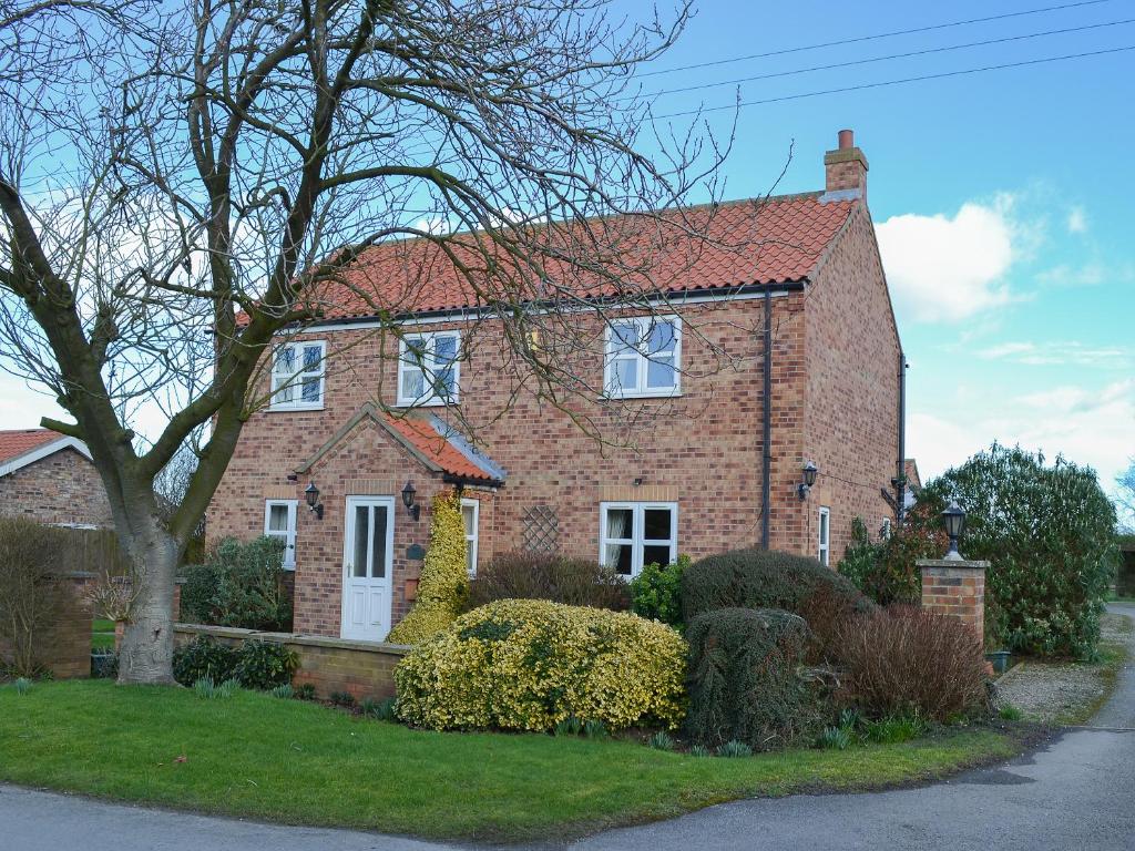 a brick house with a tree in front of it at Brompton Lodge in Ganton