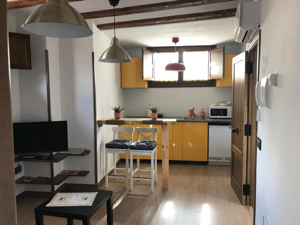 a kitchen with yellow cabinets and a table with a stool at estudio judería in Sigüenza