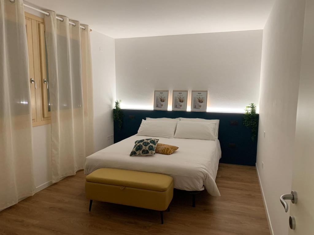 ein Schlafzimmer mit einem großen Bett mit einem gelben Hocker in der Unterkunft Appartamento 21 - Smart Apartment nel centro di Segusino, vicino le colline del Prosecco in Sequsino