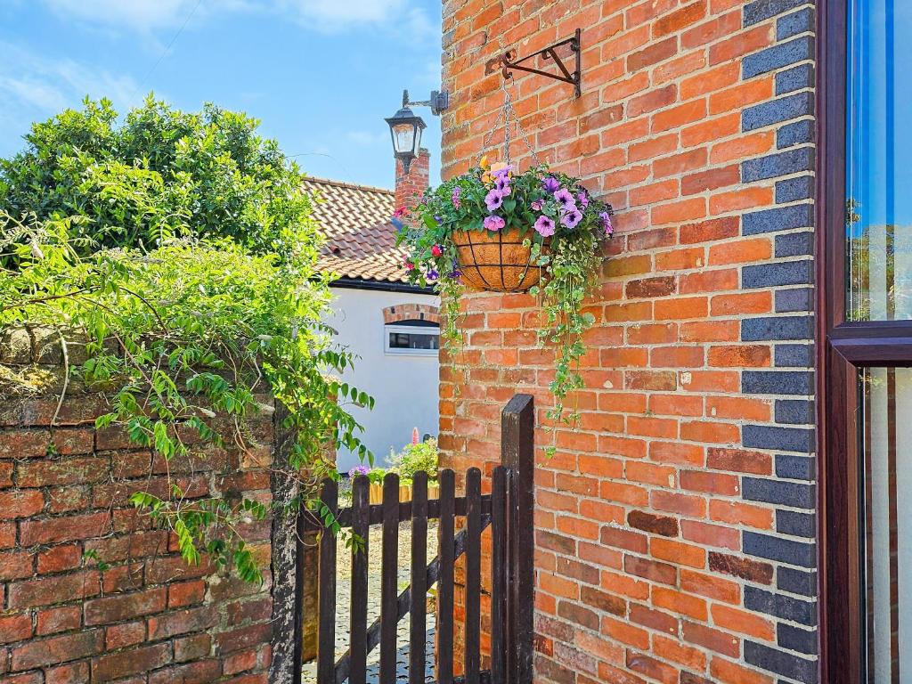 a brick wall with a flower pot and a fence at Elm Barn Lodge in Freethorpe