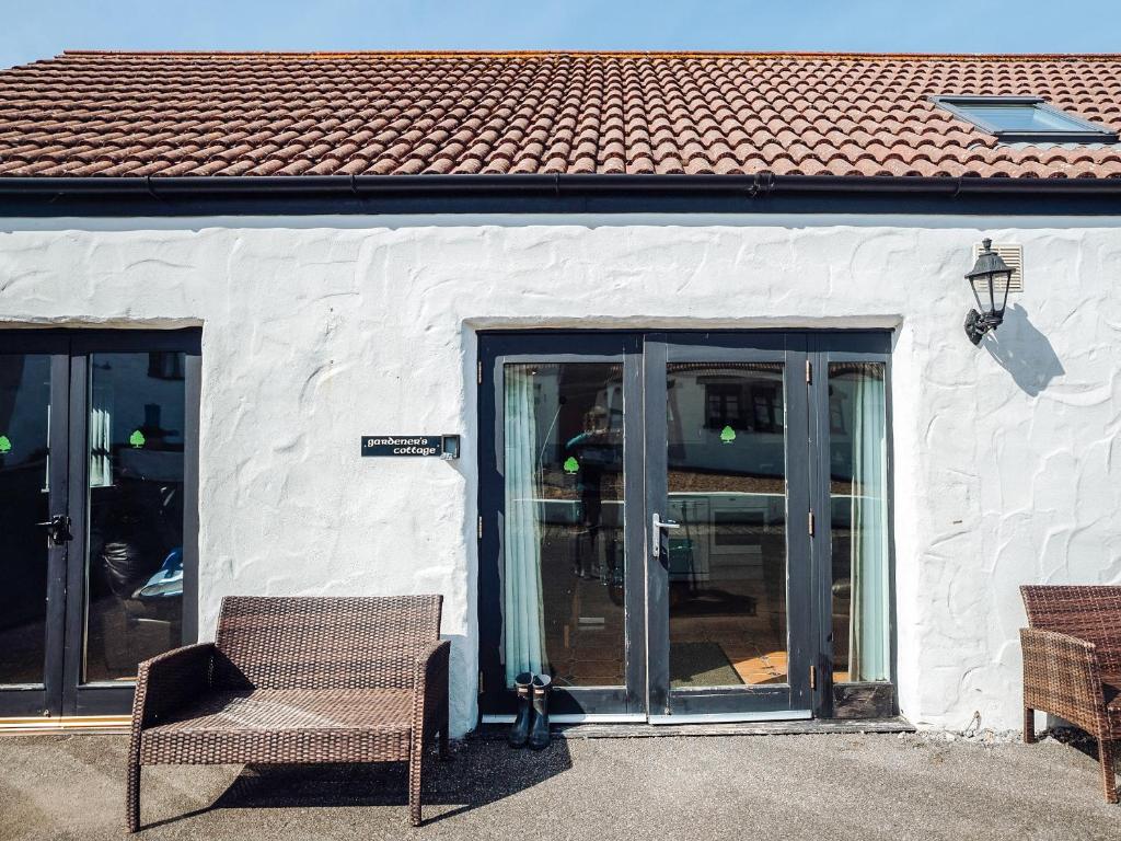 a white building with glass doors and a cat sitting in front at Gardener's Cottage - Uk6713 in Lydstep