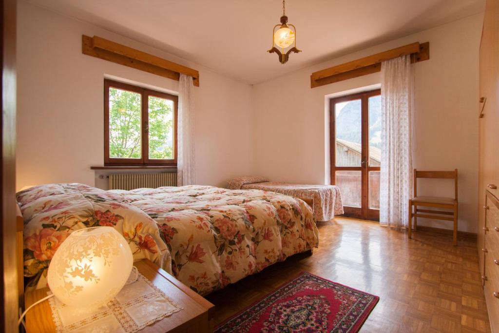 una camera da letto con un letto, un tavolo e finestre di Appartamenti Sergio Benedetti a Sappada