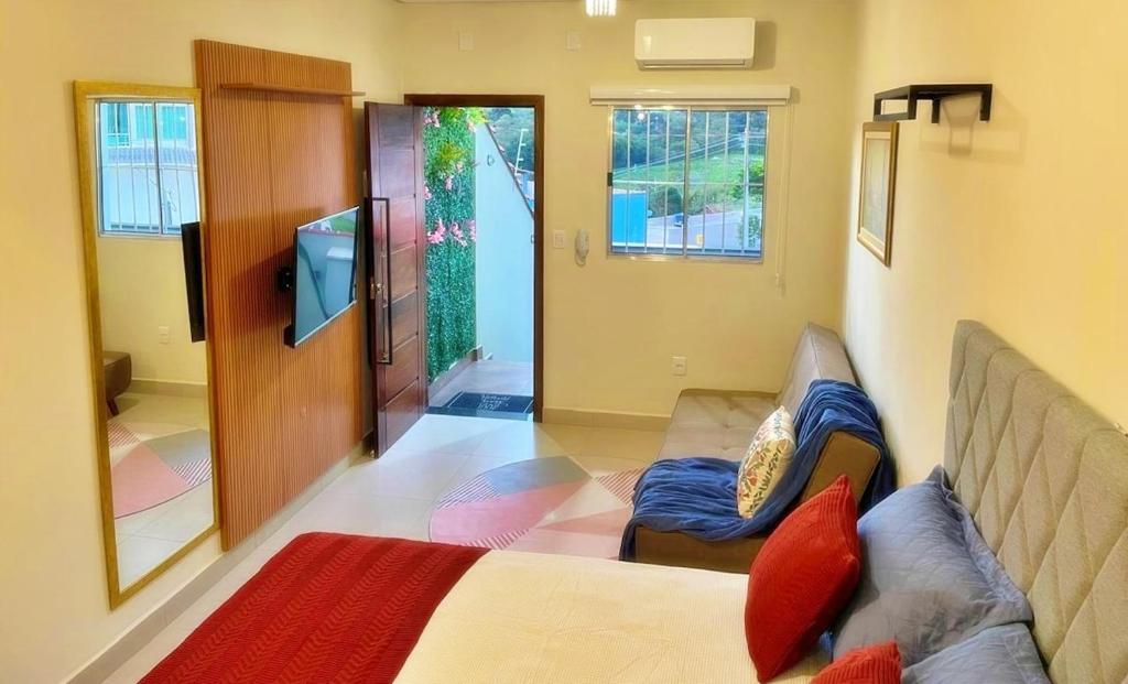 ein Wohnzimmer mit Sofa und Fernseher in der Unterkunft Estudio Novo com ar condicionado e garagem in São Lourenço
