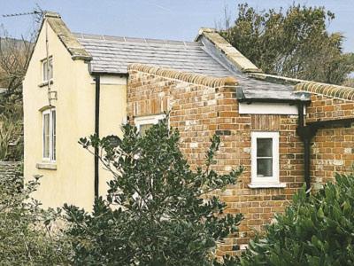 a small brick house with a tree in front of it at The Pocker Watch in Chideock