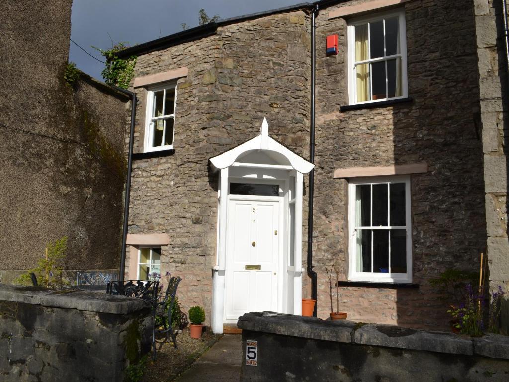 een stenen huis met een witte deur en ramen bij Church Walk Cottage in Kendal